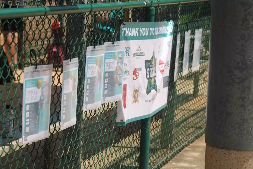 Player profile sheets and sponsor banner hanging on the dugout fence